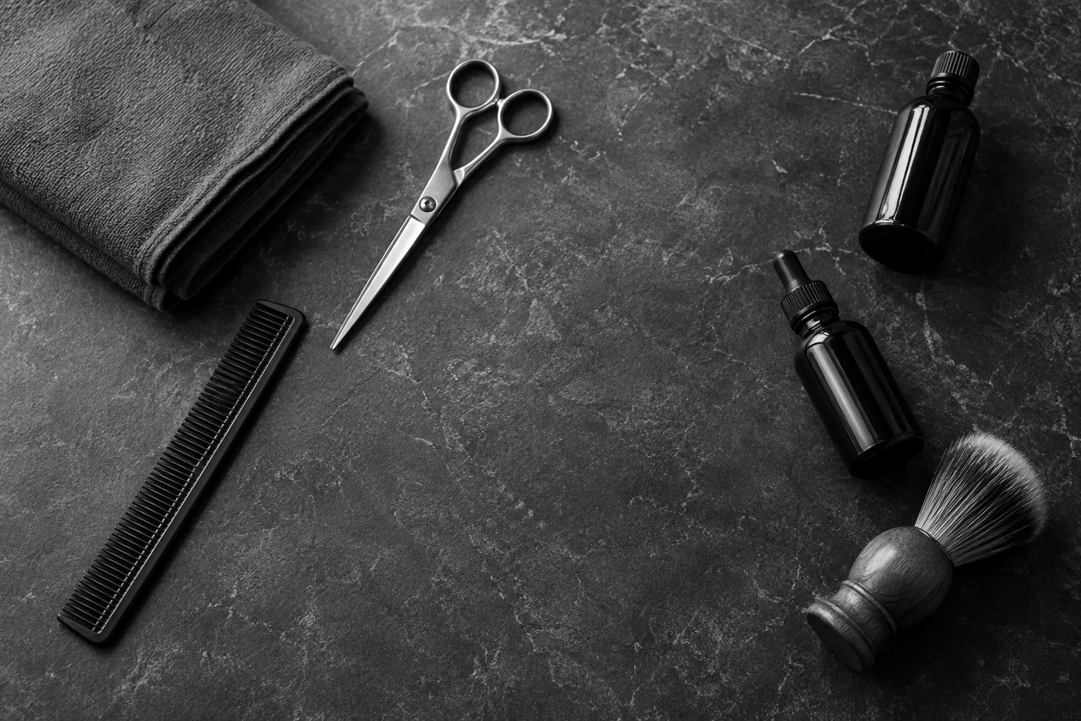 A comb, scissors, towel and grooming bottles on a dark worktop.